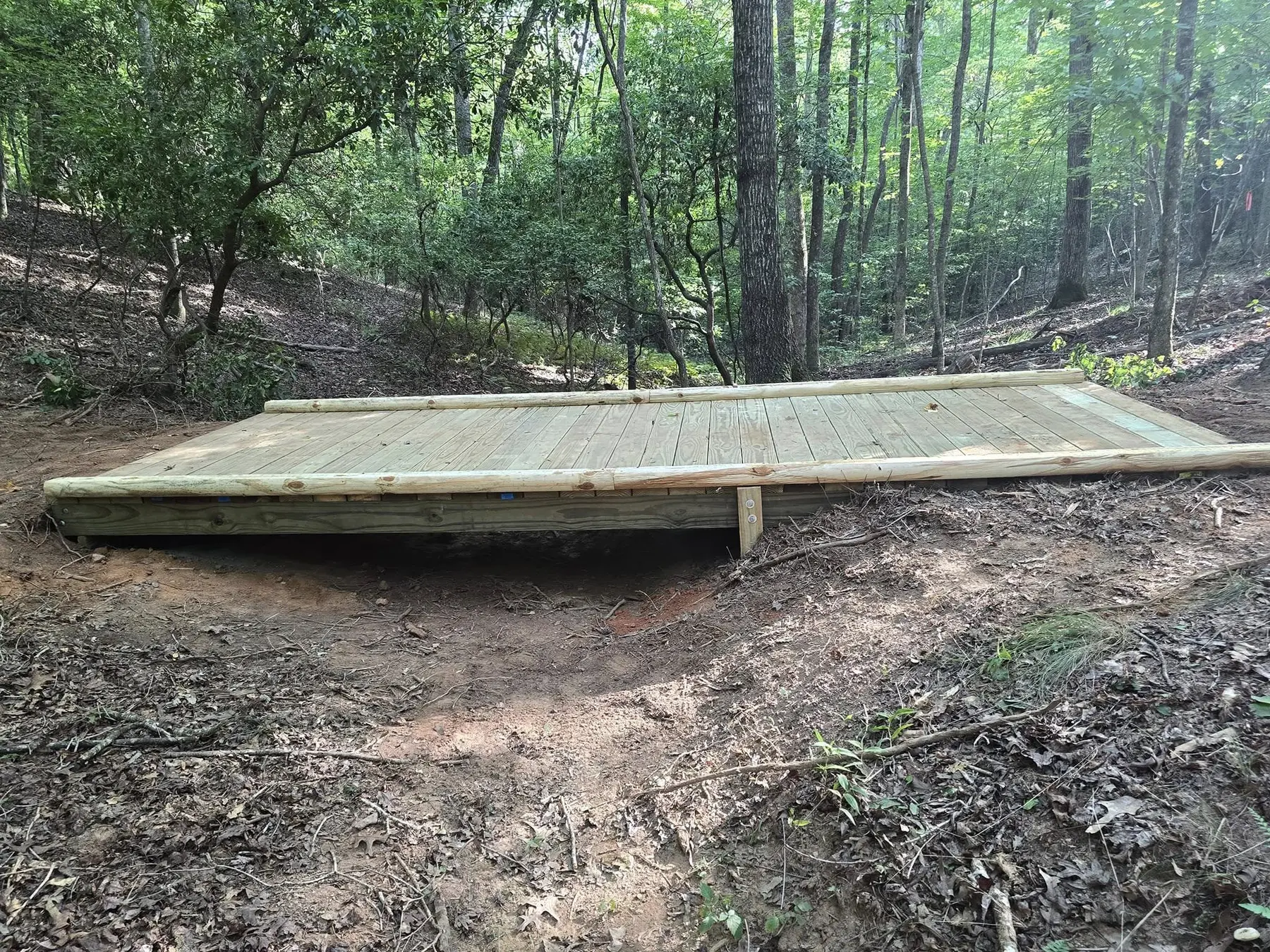 Wooden trail bridge integrated into the surrounding terrain